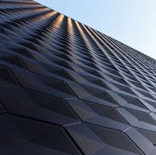 Low_angle_view_of_a_modern_building_facade_with_a_geometric_pattern_against_a_clear_sky.

