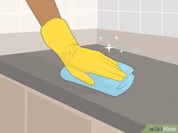 Hand_in_a_yellow_glove_cleaning_a_surface_with_a_blue_sponge.