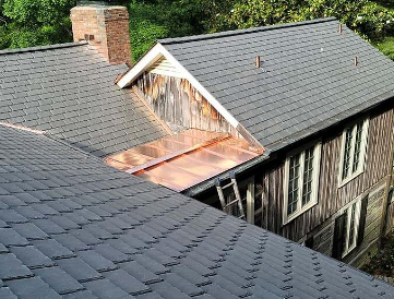 A_weathered_wooden_house_with_a_gray_shingle_roof_and_a_rusty_metal_dormer_window.