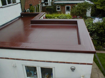 Flat_roof_of_a_building_with_brown_coating_and_a_garden_in_the_background.

